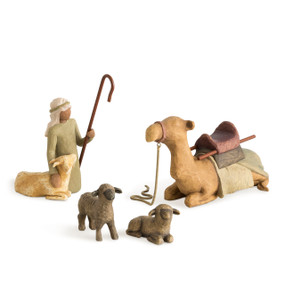 Set of four figures: kneeling shepherd in olive garment holding crook in hand with goat beside, brown camel lying down with blanket and seat on back, two dark sheep
