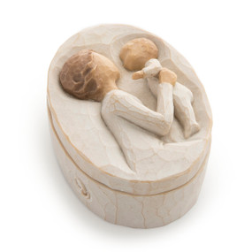 Cream oval box with lid; bas-relief carving on lid of older female in cream dress holding up baby in cream onesie