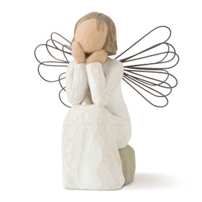 Front view of young female angel in cream dress with wire wings, seated on gray rock with hands under chin