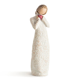 Front view of standing female figure in cream dress carved with hearts, flowers and birds with ruffled neck holding red heart in hands