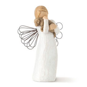 Front view of standing angel figure in cream dress with wire wings, holding brown dog in arms