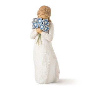 Front view of standing figure in cream dress holding large bouquet of blue flowers up to face