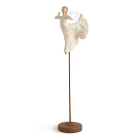 Front view of figure in ballet pose with wire wings in cream dress carved with celestial patterns, figure elevated on metal stand with base
