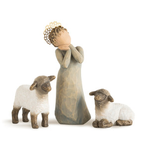 Front view of standing child figure in blue-gray dress with short curly hair and gold crown; two white sheep next to her, one standing and one lying down