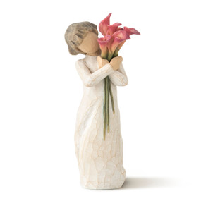 Front view of standing figure in cream dress with short brown hair holding bouquet of pink calla lillies