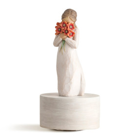 Standing figure in cream dress holding large bouquet of red-orange poppies up to face on round cream-colored base