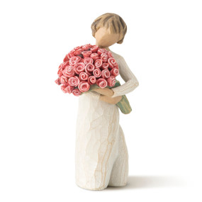 Front view of standing figure in cream dress with short brown hair carrying large bouquet of pink roses