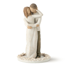 Front view of female figure in cream dress with male figure in dark pants standing behind her with arms wrapped around each other, standing on flat round base decorated with carved roses