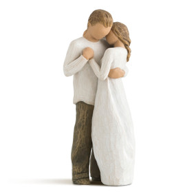 Front view of standing male and female figures, holding each other as if dancing, female in cream dress, male in cream shirt and dark pants