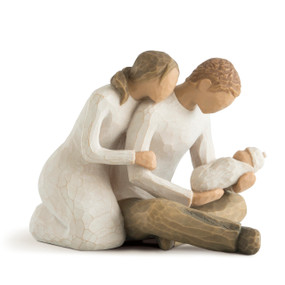 Front view of seated male and female couple figure, male cross-legged holding newborn baby, female leaning over his shoulder