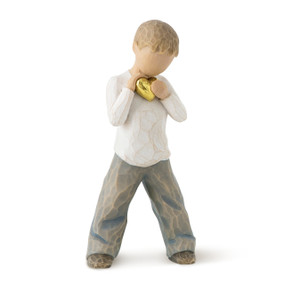Front view of standing boy figure in cream shirt and blue jeans, holding gold-leaf heart with both hands to chest