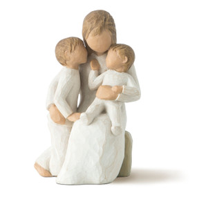 Front view of seated female in cream dress, with one arm holding small toddler, other arm around older child standing next to her