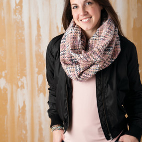 Close view of dark hair woman with black jacket and pink/grey/white scarf