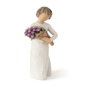 Standing figure with short brown hair wearing long cream dress holding large bouquet of purple tulips, facing front