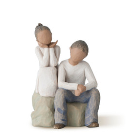 view of male and female figures with dark skin and hair seated next to each other on gray rock stand