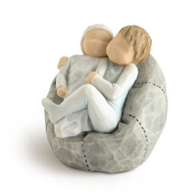 Front view of two children figures cuddling on a gray beanbag, older child in a pale blue onesie, younger in a pale blue onesie and hat