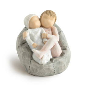 Front view of two children figures cuddling on a gray beanbag, older child in a blush pink onesie, younger in a pale blue onesie and hat