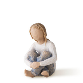 Front view of seated girl in cream shirt and blue jeans with arms wrapped around knees