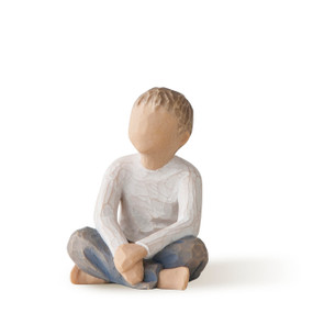 Front view of cross-legged boy in cream shirt and blue jeans, with hands folded in lap