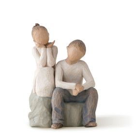 Boy and girl figures, seated next to each other on a rock, girl in cream dress with hair up, boy in cream shirt and blue jeans