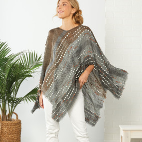 Front view of blonde woman wearing light grey/brown/white dotted shawl with white jeans standing up