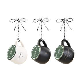 A set of three black and white coffee pod mug ornaments filled with green coffee pods.