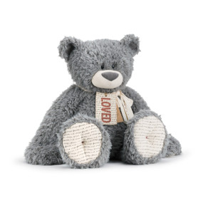 A soft fluffy gray and white plush bear with a "loved" fabric tag, a cream and red ribbon, and a cardboard product tag.