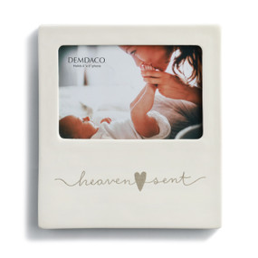 An ivory picture frame with "heaven sent" engraved.