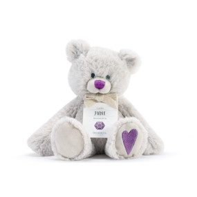 A fluffy white plush bear with a purple nose, purple heart, and a white product tag that reads "Lucky June".
