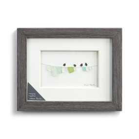 A gray frame enclosing a pebble scene of birds on a clothesline.