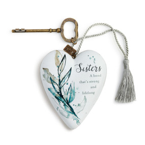 A light blue art heart with a blue floral print and a message about sister's. With a silver tassel and bronze key.