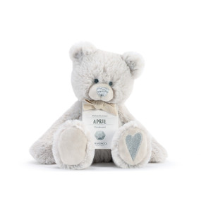 A fluffy white plush bear with a silver nose, silver heart, and a white product tag that reads "Adventurous April".