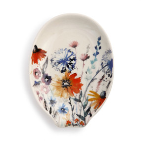 An ivory oval shaped spoon rest with a floral print pattern.