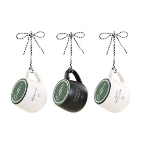 Three black and white coffee pod mug ornaments filled with green coffee pods and hung with black and white striped rope.