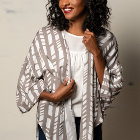 A woman wearing a white blouse, dark denim jeans, and a taupe and white "Tie Front Duster".