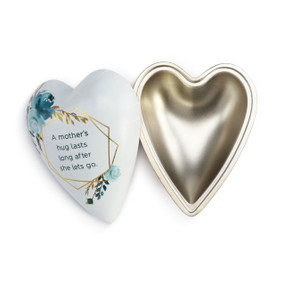 Metal trinket box in heart shape with a white lid stating A mother's hug lasts long after she lets go.