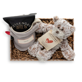 A brown gift box filled with a "love" coffee mug filled with a bag of Messenger Coffee, and a brown plush teddy bear.