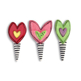 A set of three heart shaped cupcake toppers with black and white striped bases.