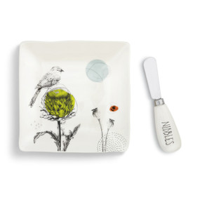 A white plate with black flowers and a bird. Placed beside a matching spreader.