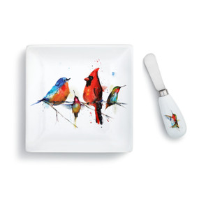 A white plate with four little birds painted on the front. Placed by a matching spreader.