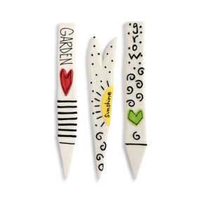 A set of three white garden plat picks with various designs.