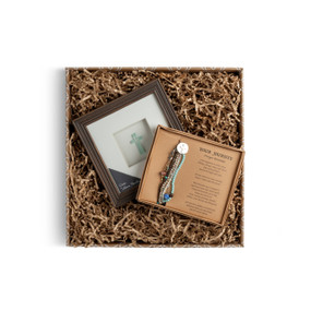 A brown gift box filled with a framed pebble cross and a "Your Journey" bracelet set.
