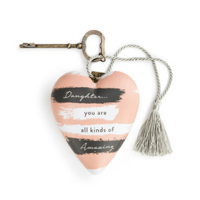 A pink art heart with black and white stripes and reads "daughter... you are all kinds of amazing", a metal key, and a gray tassel.
