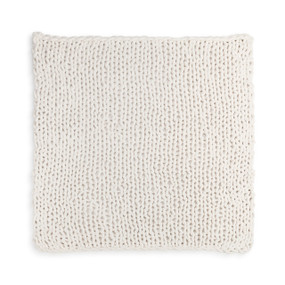 A large, soft, chunky knitted cream blanket.
