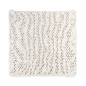 A large, soft, chunky knitted cream blanket.