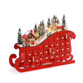 A red sleigh shaped Advent calendar with 24 small drawers and a lit holiday scene on top