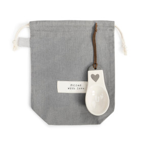 A gray coffee bag that reads "filled with love" pictured with a matching white scoop.