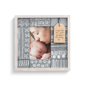 A gray picture frame with 8 gray patches, each with a different pattern, such as stripes. Enclosed in a light wooden frame. Enclosing a picture of a mother kissing her baby. With a wooden hang tag that reads sweet little one... grow up happy and strong"."