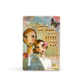 A cream rectangular plaque with a collage of patterns, two young sisters, and reads I count my lucky stars for you. Every single day." in black typewriter font."