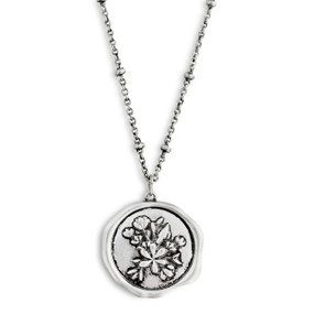 A close up image of a circular pendant with a flower bouquet on a dainty silver necklace.